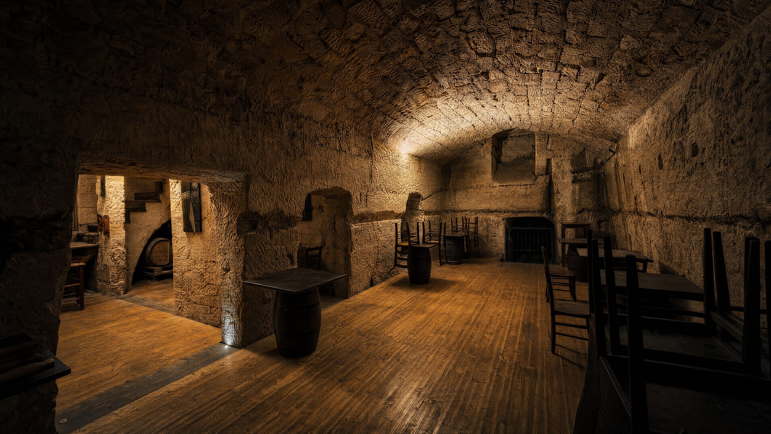 La sala voltata in pietra del Birrificio Isola a Thiesi, con le botti in legno come tavoli e il camino sul fondo